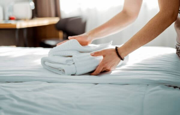 Układanie ręczników na czystym łóżku hotelowym
