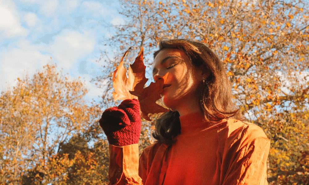 Kobieta cieszy się jesiennym dniem trzymając liść